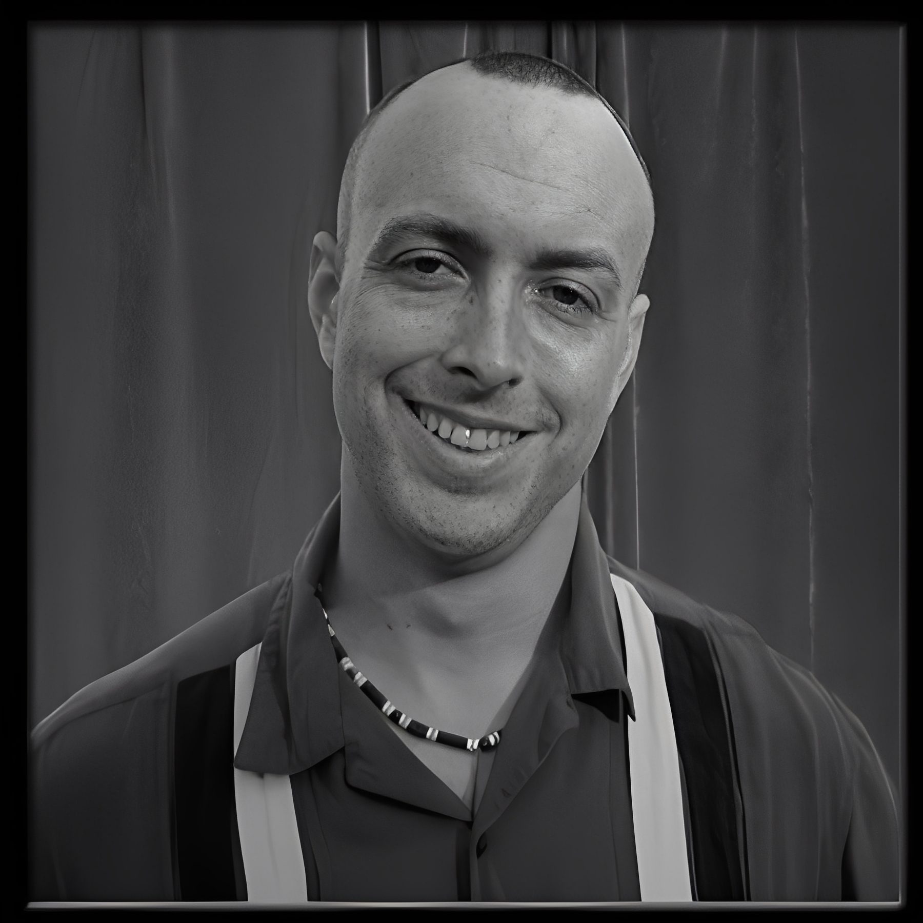 Smiling bald man wearing necklace and suspenders
