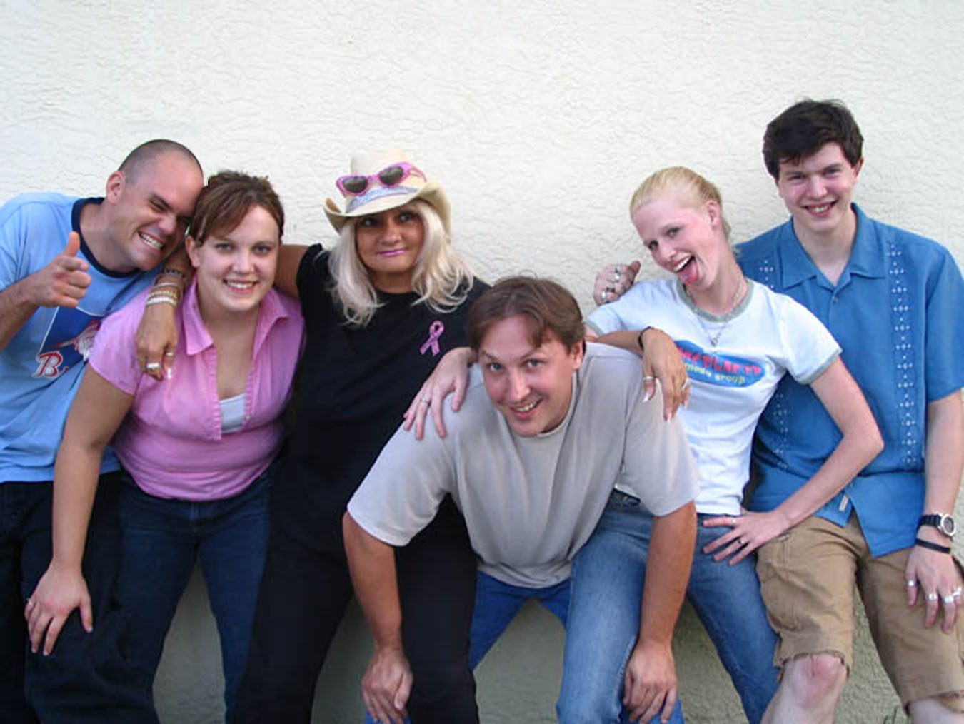 Six friends smiling and posing against wall
