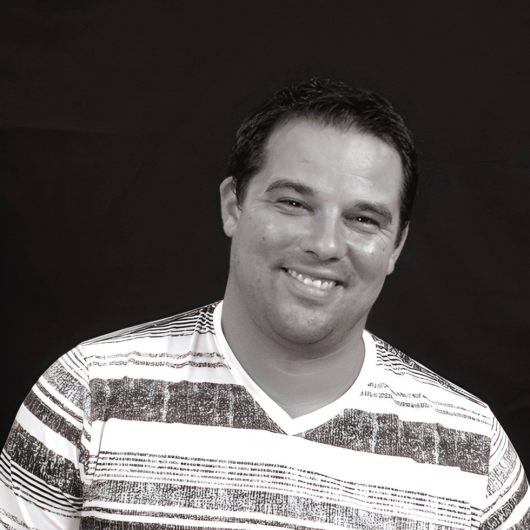 Smiling man wearing striped shirt, dark background